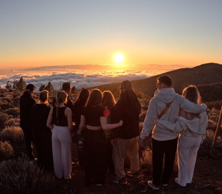Gran grupo de personas contemplando la espectacular puesta de sol sobre el mar de nubes en el Parque Nacional del Teide durante la excursión Sunset Trip en Tenerife.